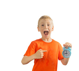 a boy in an orange T-shirt with emotions on his face holds an alarm clock and points at it