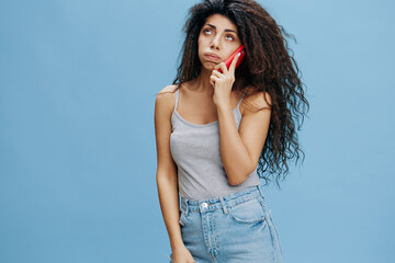 ONLINE CALL AD CONCEPT. Frustrated beautiful curly Latin lady hold pink smartphone in hand, have...