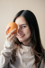 attractive cheerful asian woman holding orange or grapefruit , beauty and healthy skin care and cosmetic ideas concept