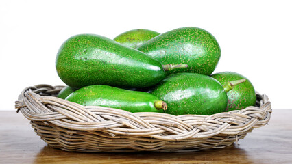 avocados in basket on wooden table on white background