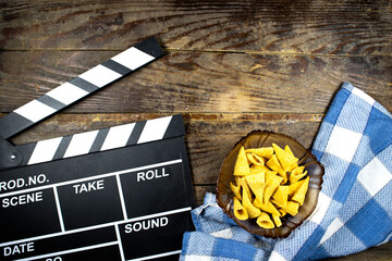 clapper board of video cinema in studio, cone corn chips in glass bowl on wooden table