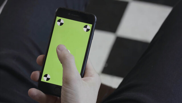 Man Hands Using Mobile Smartphone With Green Screen, Over The Shoulder View. Stock Footage. Close Up Of Man Scrolling And Tapping On Iphone Screen With Chroma Key.