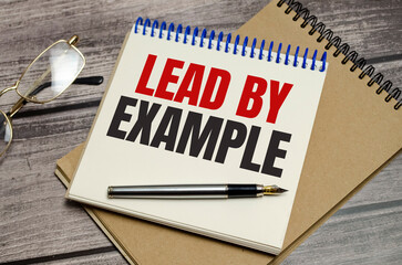 lead by example words on notepad and wooden background