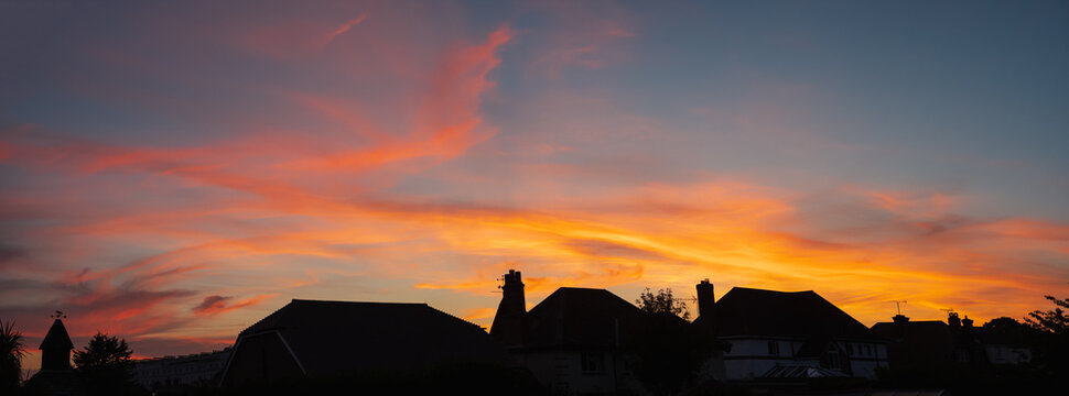 Panoramic silohette of roof tops at sunset. The sky has beauty golden clouds.