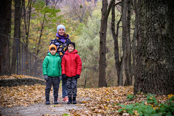 Fototapeta premium Mother and her children boys are playing together on autumn walk