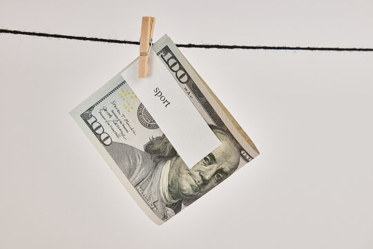 A $100 bill with the words "sport" on it hung on a clothesline.