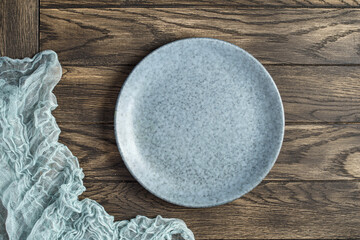 Empty bluish plate and gauze napkin on oak woodentable. Top view, with copy space