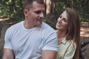 Young beautiful couple hugging, sitting on a motorcycle, travel together on a forest road