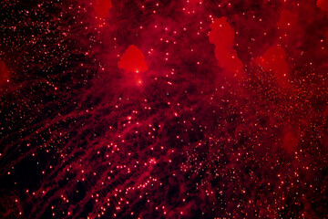 A bright firework with a red glowing center with red sparks and smoke flying towards the background...