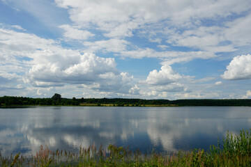 White clouds and reflection in the lake. Open spaces. Horizon. Summer