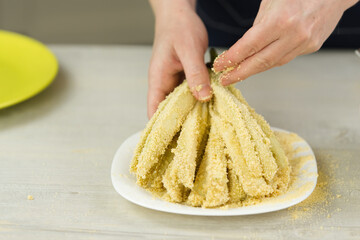 Coating sliced eggplant with breadcrumbs. Woman is cooking tasty snacks at home. close up