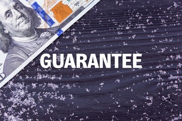 GUARANTEE - word (text) on a dark wooden background, money, dollars and snow. Business concept (copy space).