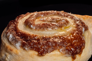 One cinnamon bun baking and rising on tray in electric oven - close up view. Swedish cuisine, homemade bakery, food, cooking and pastry concept