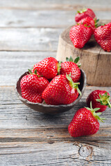 Ripe red strawberries from organic cultivation offered as a close-up in a rustic design bowl on old faded wood