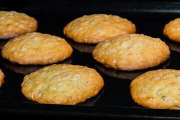 Many baked homemade crunchy oatmeal cookies on metal sheet in oven - close up. Dessert, cookery, baking, gastronomy concept