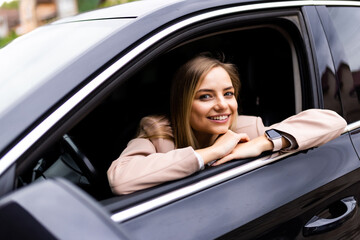 Young woman driving a car and holding a cup of coffee