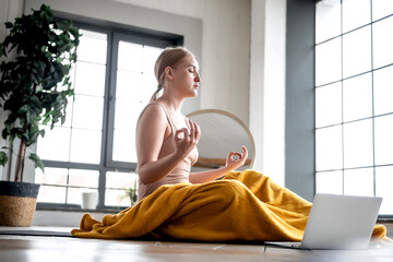 Fototapeta na wymiar Young blonde woman meditating in an online class