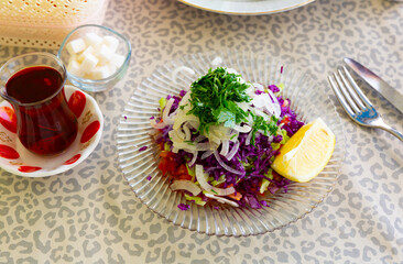 Colorful refreshing salad from chopped red cabbages, cucumbers, tomatoes and onion garnished with...
