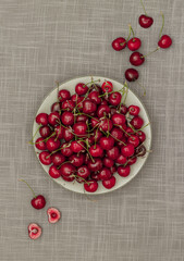 Juicy sweet cherry on a white plate on a gray background 