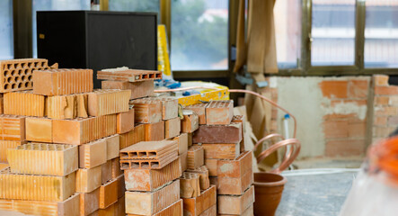 Red bricks and other construction materials stacked before renovation at indoor building construction site