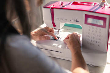 Obraz na płótnie Canvas woman manipulating sewing machine to set the threads