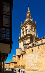 Fototapeta na wymiar View of street in historical area of El Burgo de Osma overlooking Gothic bell tower medieval Roman Catholic Cathedral of Assumption with pointed spire and dome with figured turrets on sunny day, Spain