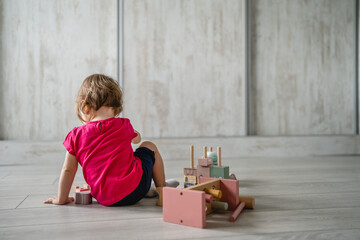 one child small caucasian girl little toddler playing with educational toys at home childhood and growing up early development concept copy space back view