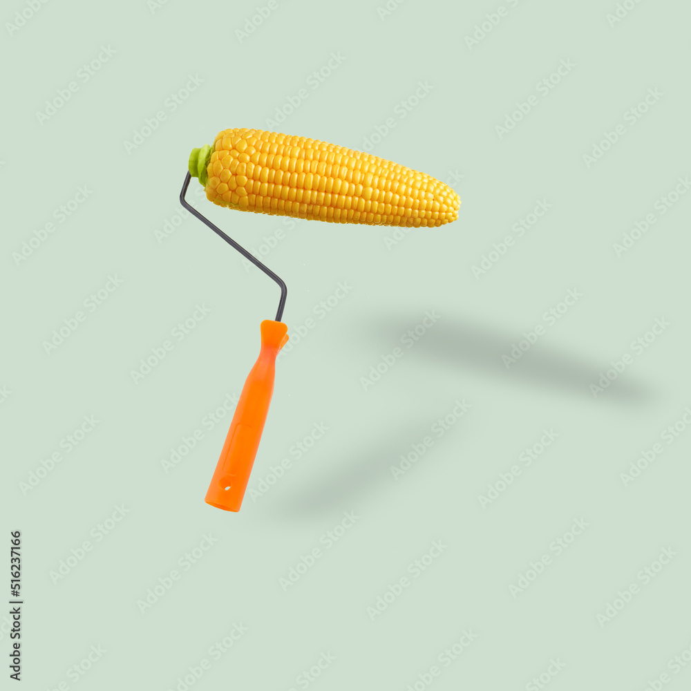 Wall mural Unusual combination of usual things. Orange paint roller as an fresh corn cob flying on pastel blue background. Modern design. Copy space. Contemporary art. Creative conceptual and colorful collage.