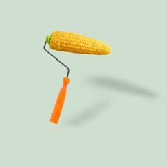 Unusual combination of usual things. Orange paint roller as an fresh corn cob flying on pastel blue background. Modern design. Copy space. Contemporary art. Creative conceptual and colorful collage.