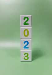 Cube tower with colorful numbers 2023 in center of the photo on green background. New year, calendar.