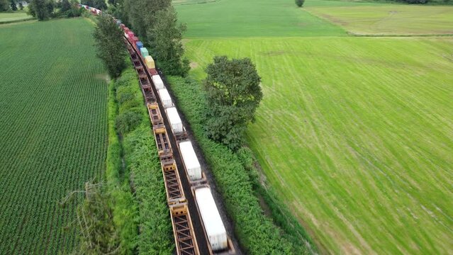 Aerial shot of a train carrying containers traveling through a rural countrside scene in Chilliwack British Columbia Canada