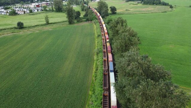 Aerial shot of a train carrying containers traveling through a rural countrside scene in Chilliwack British Columbia Canada