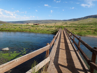 wooden bridge leading to fields over a river