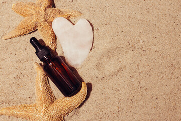 Serum or Liquid Collagen dropper bottle on sand background with sunlight. Anti age Cosmetics products concept. View from above. 