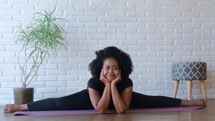 A swarthy woman sits on cross twine. Smiling. Strengthens the muscles in the hips, abdomen, back...