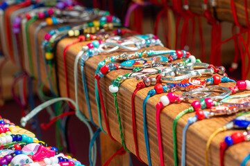 Fototapeta na wymiar A table of decorative colorful cosmetic beads of luxury objects. The glamour balls, plastic jewelry, fashionable necklaces, and bracelets are laid out in a bazaar. The trinkets are of multiple colors