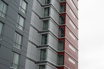 The exterior wall of a contemporary commercial style building with aluminum metal composite panels and glass windows. The futuristic building has engineered diagonal cladding steel frame panels.  