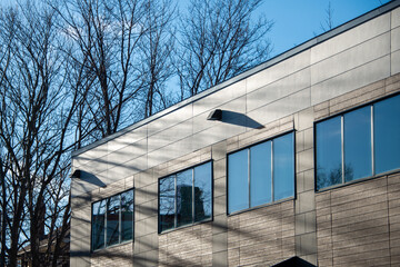 The exterior wall of a contemporary commercial style building with aluminum metal composite panels and glass windows. The futuristic building has engineered diagonal cladding steel frame panels.