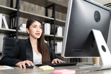 Portrait of pretty business woman using computer at workplace in an office. positive business lady smiling looking into screen of computer.