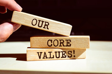 Our core values symbol. Businessman hand. Wooden blocks with words 'Our core values'.