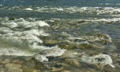 Stormy threshold of a rocky bank of a mountain river shot close-up.