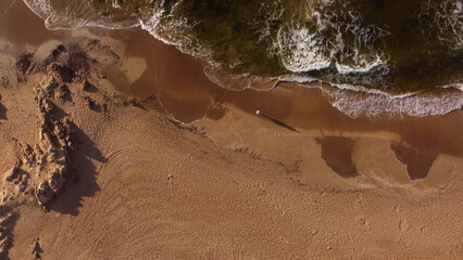 One person strolling on sandy beach at sunrise, Punta del Este in Uruguay. Aerial top-down view.