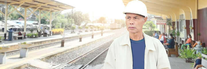 An elderly Asian man is waiting for a car on a train platform.