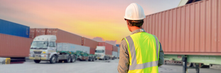 Fototapeta premium A truck driver wearing a helmet stands in a parking lot.