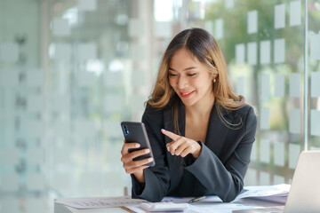 Beautiful Asian business woman using on smart phone in office.