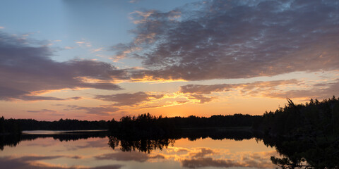 sunset with clouds over a forest lake