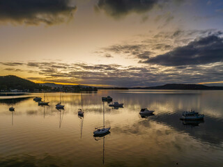 Aerial sunrise waterscape with boats, reflections and cloud filled sky