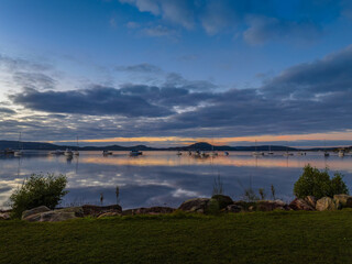 Obraz premium Aerial sunrise waterscape with boats, reflections and cloud filled sky
