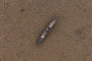 wooden boat on dry cracked earth top view. Climate change and Drought impact people, fisherman...