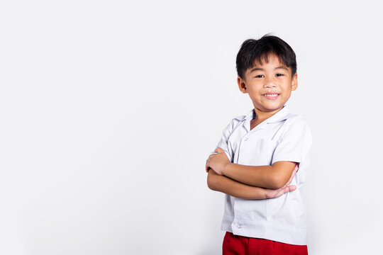 Asian toddler smile happy wearing student thai uniform red pants stand with arms folded in studio shot isolated on white background, Portrait little children boy preschool crossed arms, Back to school